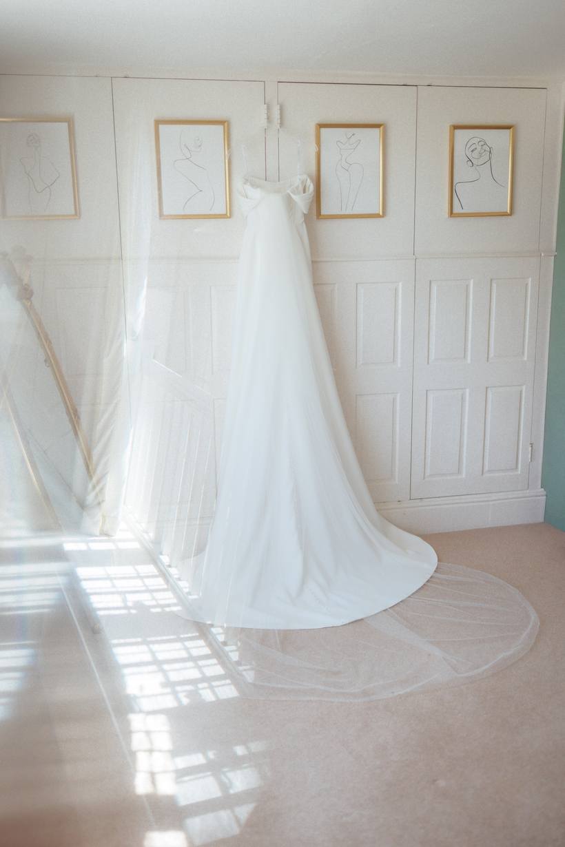 A wedding dress hanging in a bright window
