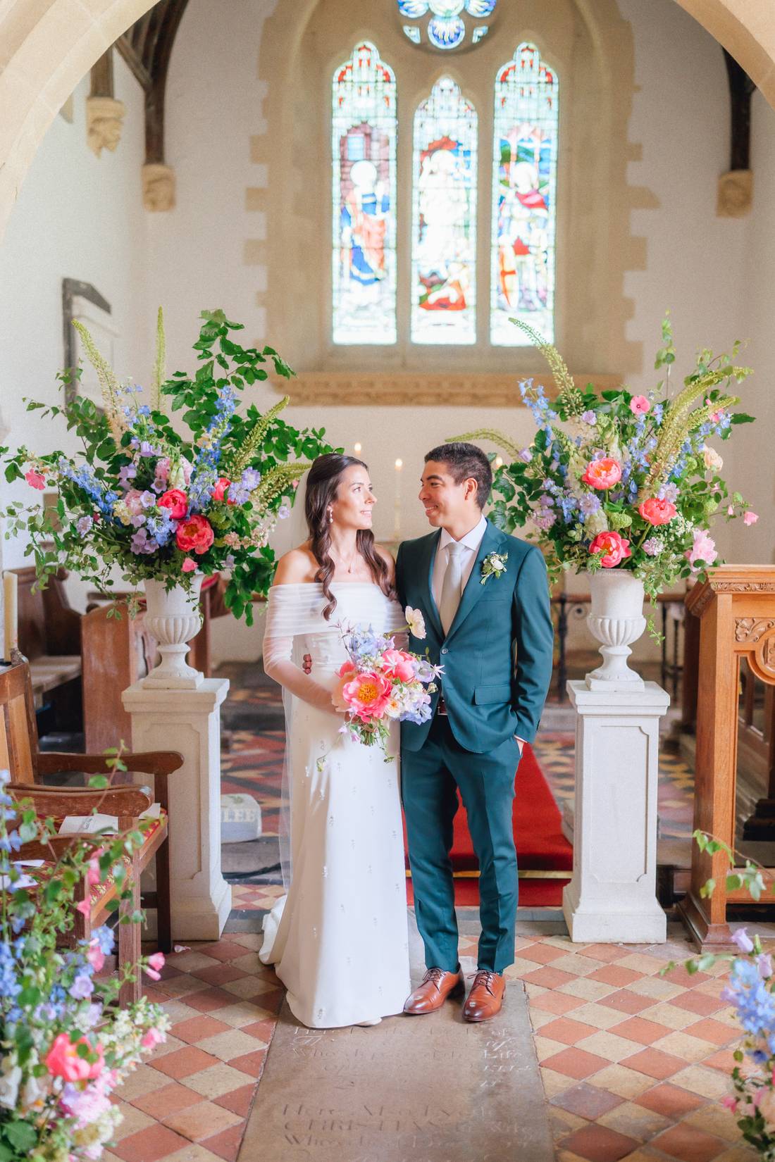 A couple at the altar of a small church filled with bright flowers