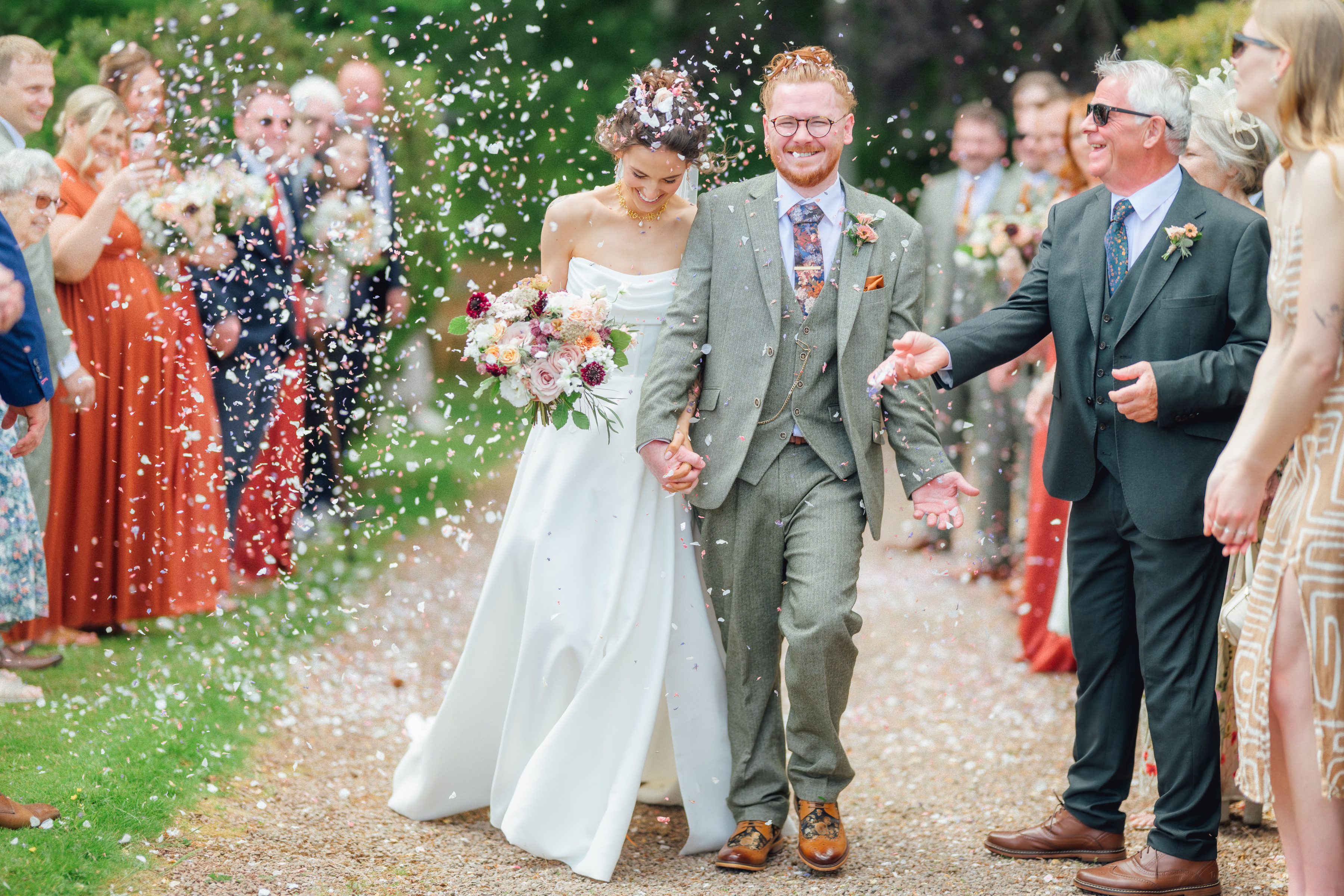 Emma and Alistair walking through confetti at Broadfield Court